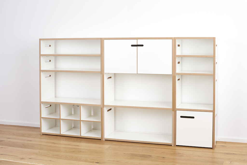 Tojo Halbstark Regalsystem: Weißes, modulares Regalsystem mit offenen Fächern, Schubladen und Schrankelementen für flexible Wohnraumgestaltung.