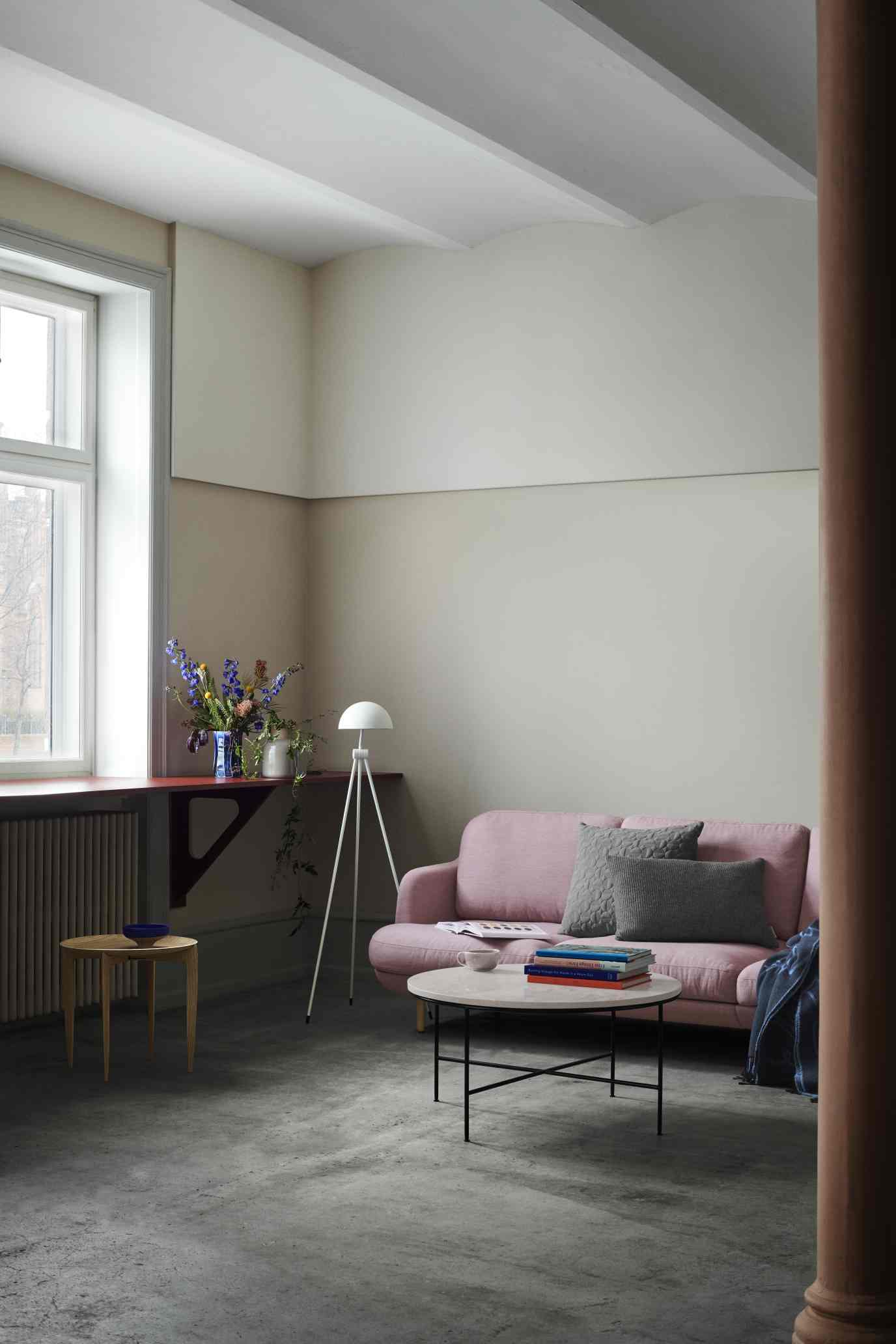 Rosa Fritz Hansen Lune Sofa mit grauen Kissen in einem hellen Wohnzimmer mit Couchtisch.