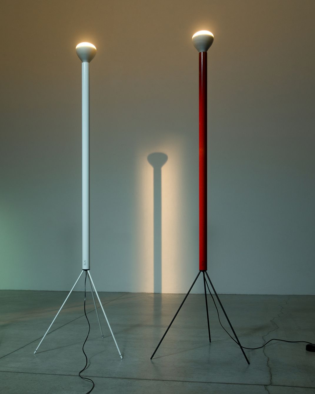 Zwei moderne Stehlampen, darunter die weiße Flos Luminator, mit filigranem Dreibein-Gestell.