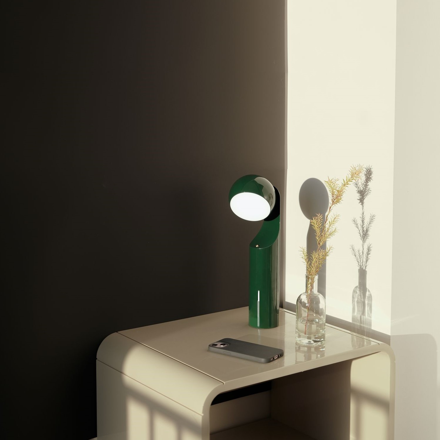 Grüne Mono Portable Akkuleuchte von house of home auf einem Nachttisch.