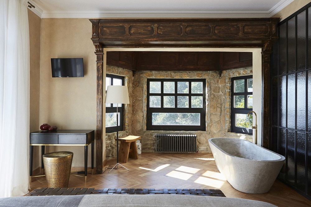 Santa & Cole Pie de Salon Stehleuchte im luxuriösen Badezimmer mit Steinwand und freistehender Badewanne.