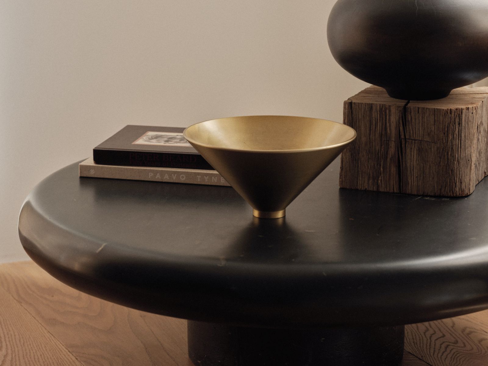 Goldene Audo Copenhagen Taper Schale auf schwarzem Tisch, dekorative Wohnaccessoires und modernes Design.