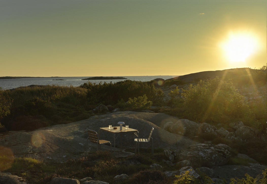 Normann Copenhagen Vig Table Outdoor auf Felseninsel mit Meerblick im Sonnenuntergang.