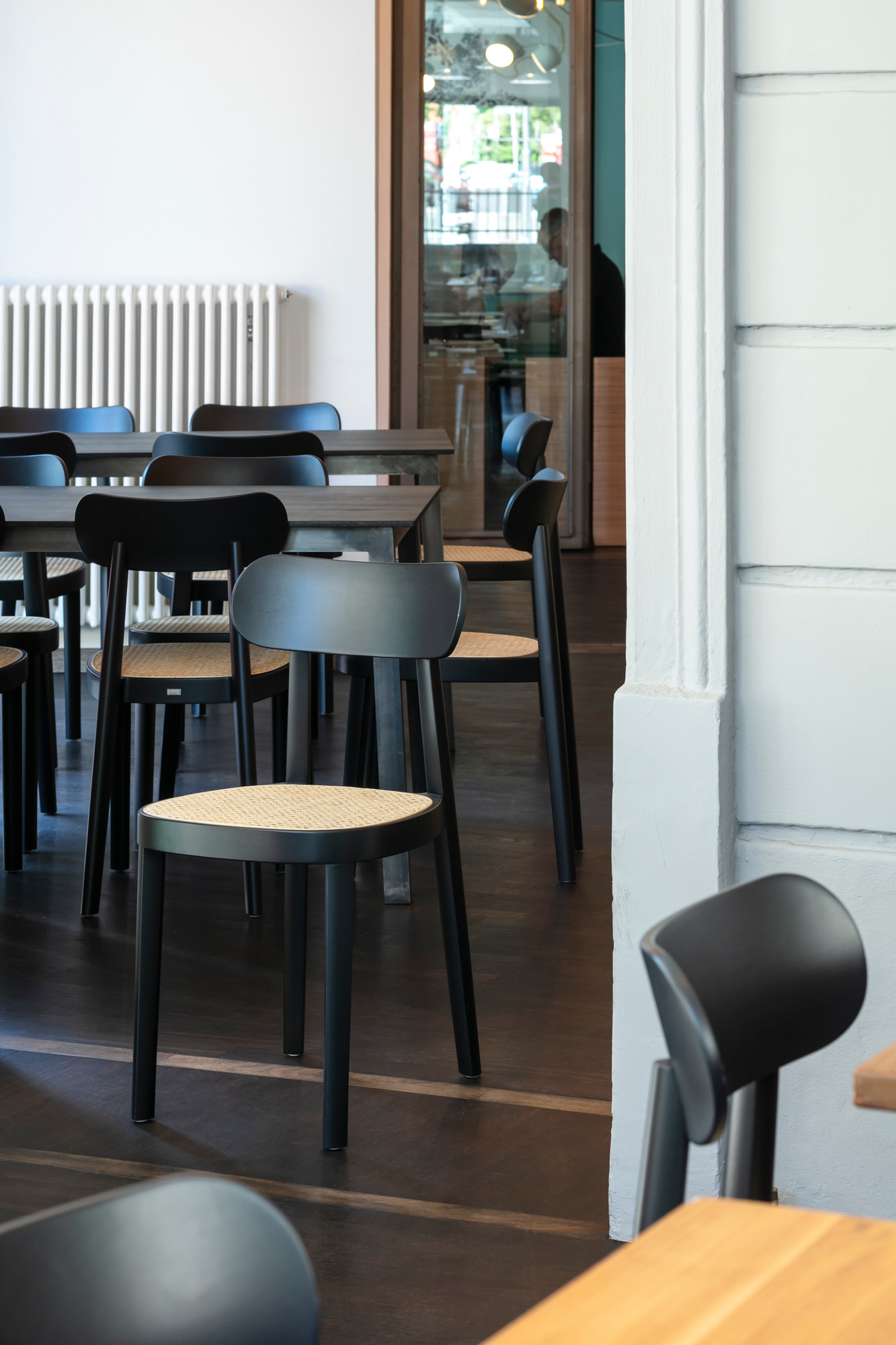 Schwarzer Holzstuhl Thonet 118 mit Wiener Geflecht Sitzfläche in einem modernen Restaurant, Stühle im Fokus.