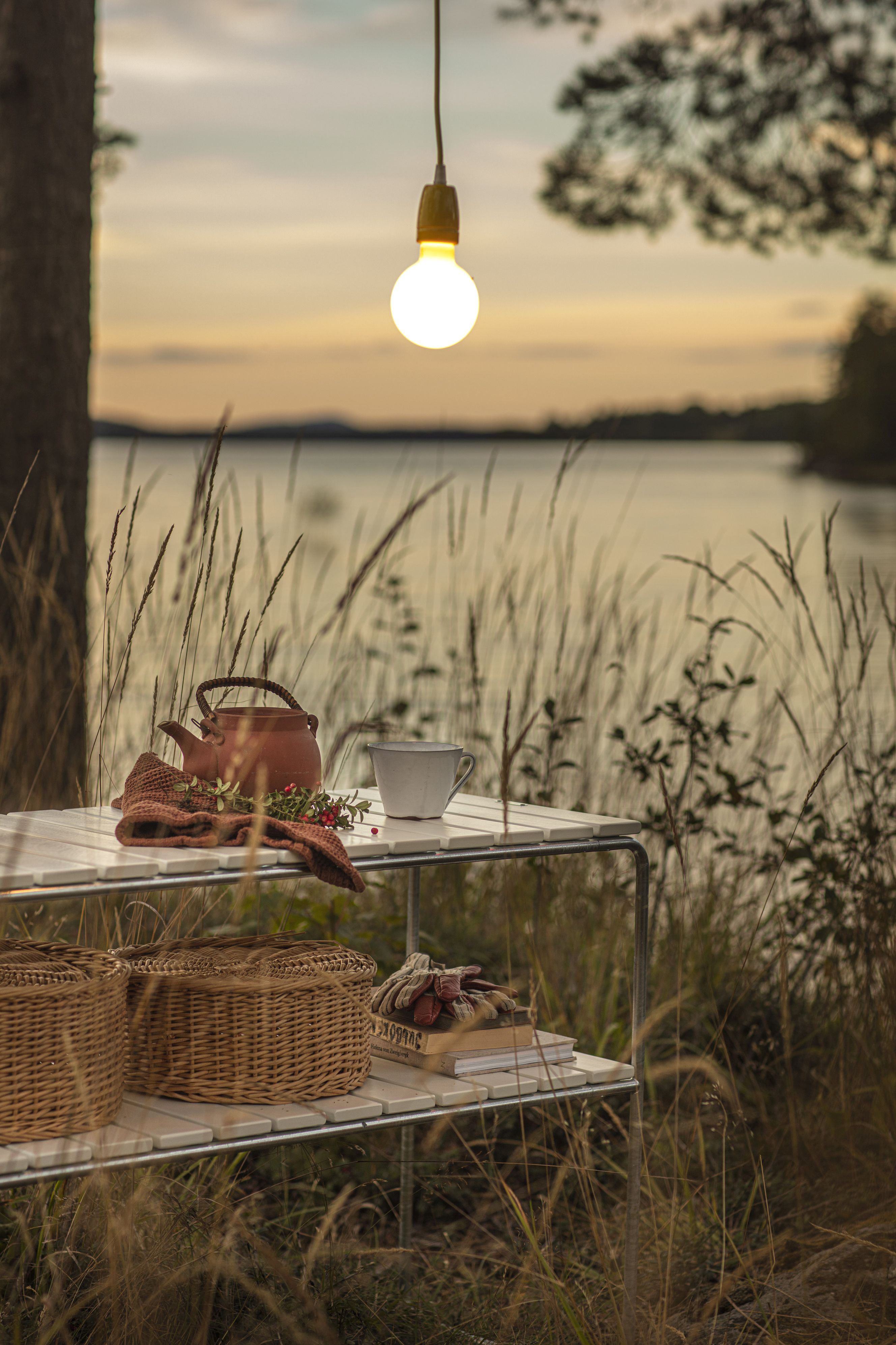 Grythyttan Stalmöbler Beistelltisch L105 Eiche: Outdoor-Szene mit Teekanne, Tasse und Körben auf dem Tisch.