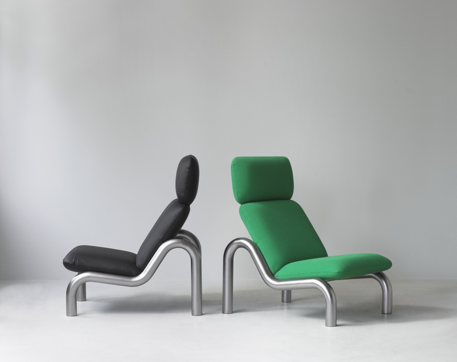 Zwei Tube Lounge Chairs von Normann Copenhagen, einer schwarz, einer grün, mit Stahlrahmen.