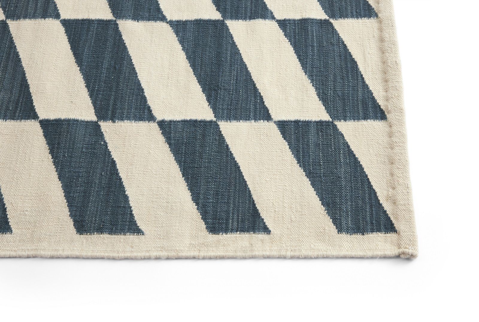 Detailaufnahme des Shift Kelim Teppichs von Hay mit blau-weißem Rautenmuster und gewebter Textur.