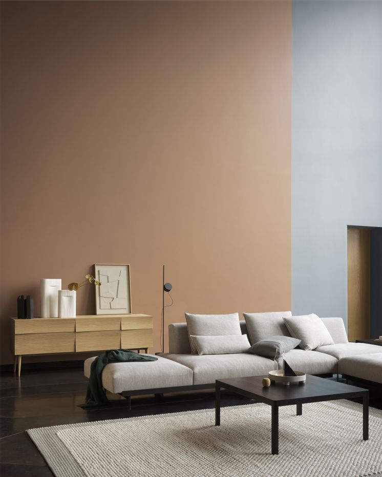 Helles Wohnzimmer mit modularem Sofa, Couchtisch, Teppich und Holzkommode im modernen Design.