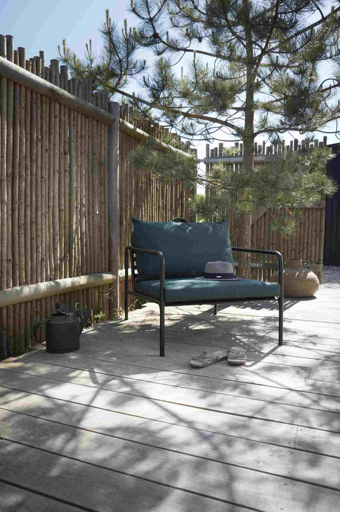 Avon Lounge Chair Outdoor Sessel von Houe auf Holzterrasse mit Dekoration und Gartenzaun im Hintergrund.