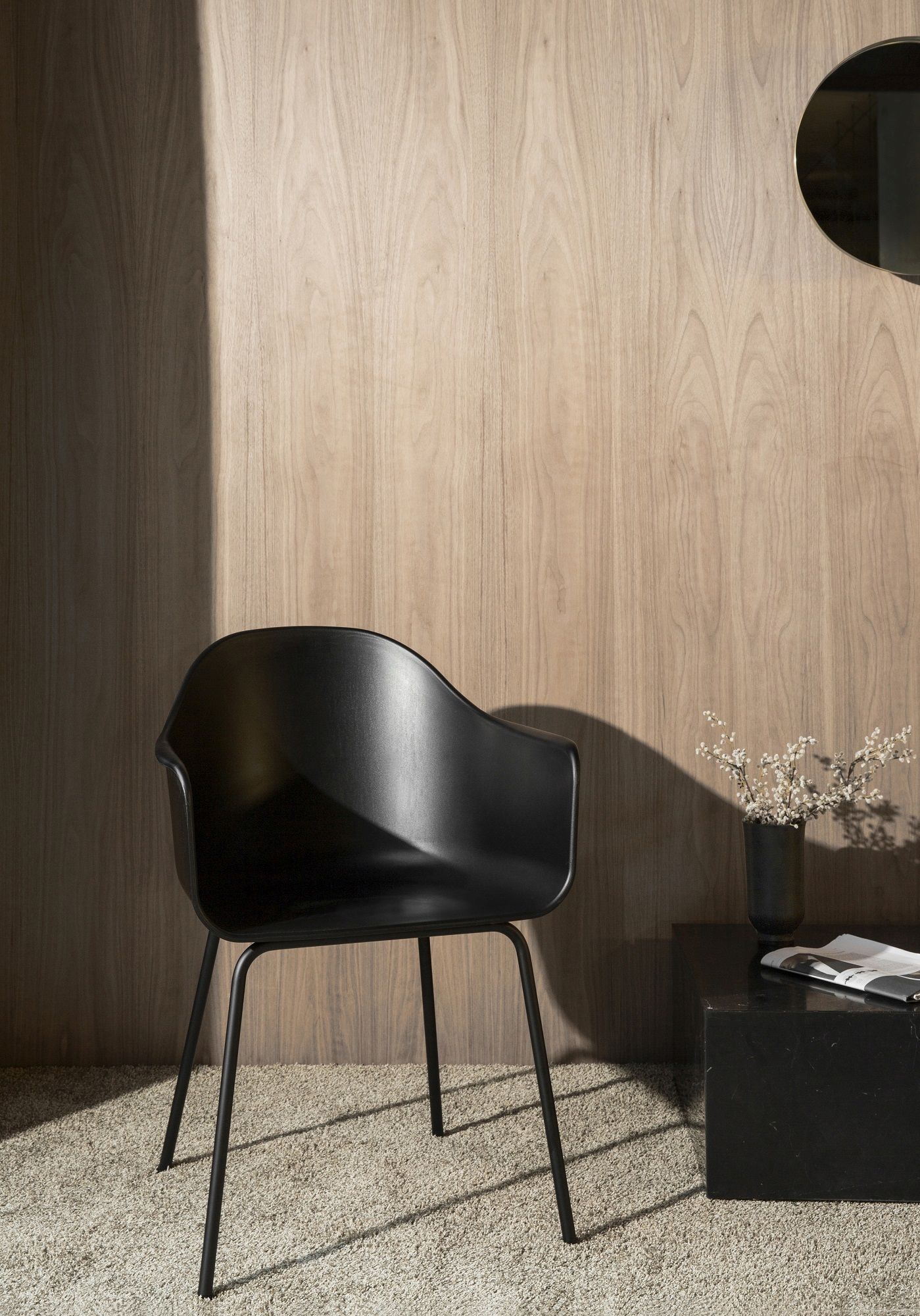 Schwarzer Harbour Dining Chair Stuhl von Audo Copenhagen vor einer Holzwand und einem Beistelltisch.
