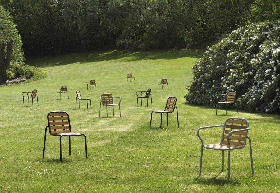 Mehrere Normann Copenhagen Vig Chair Gartenstühle auf einer grünen Wiese, ideal für den Außenbereich.
