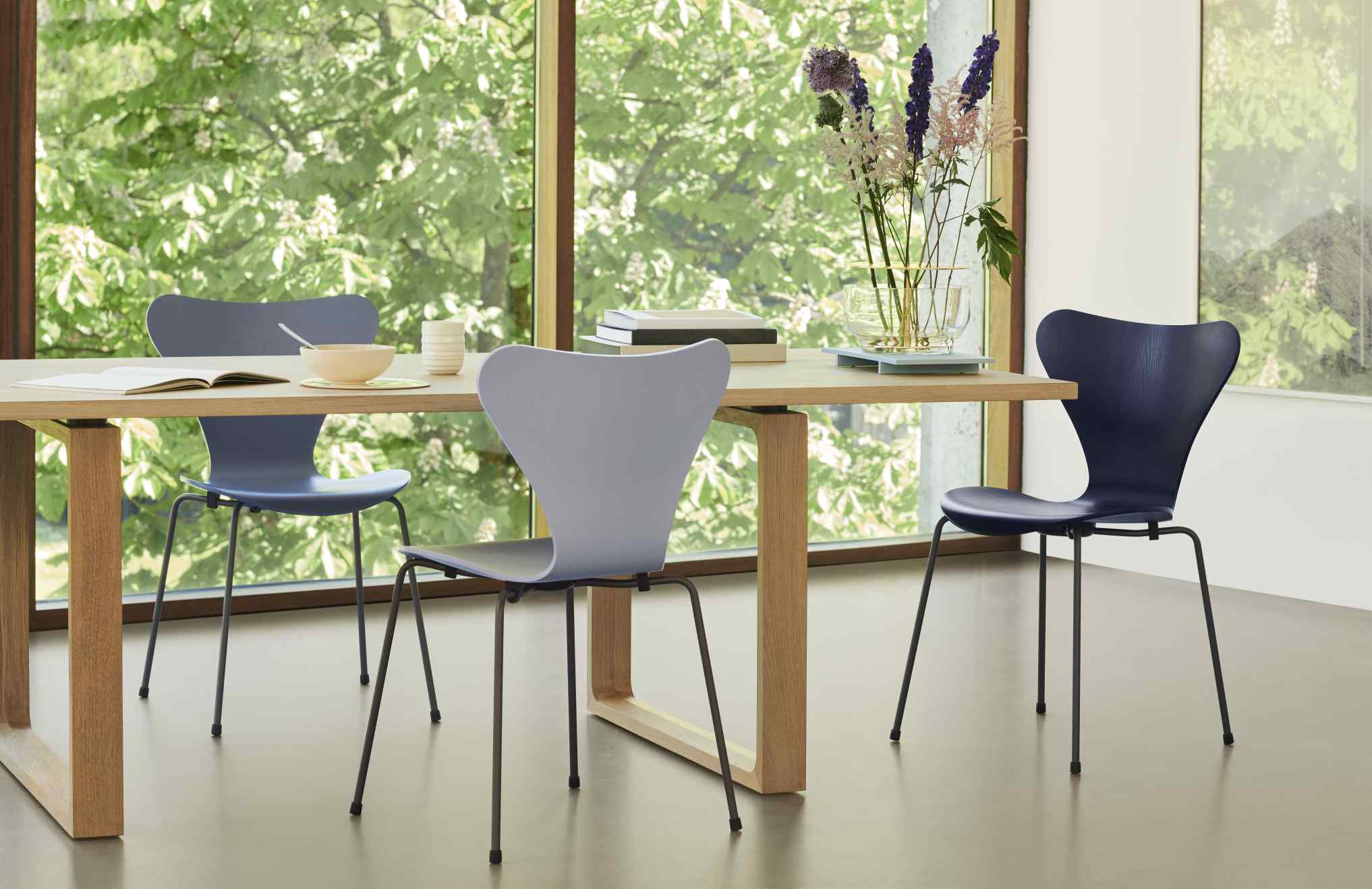 Essay Tisch von Fritz Hansen mit Stühlen und Dekoration vor einem Fenster.