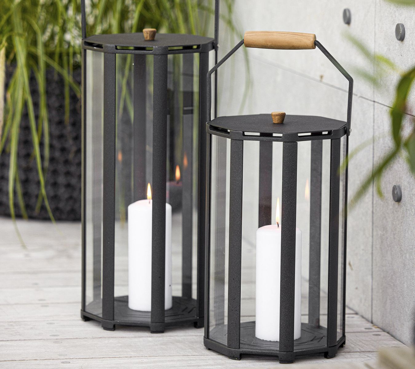 Zwei Cane-Line Lightlux Laternen aus Teakholz und Glas mit brennenden Kerzen im Innenbereich.