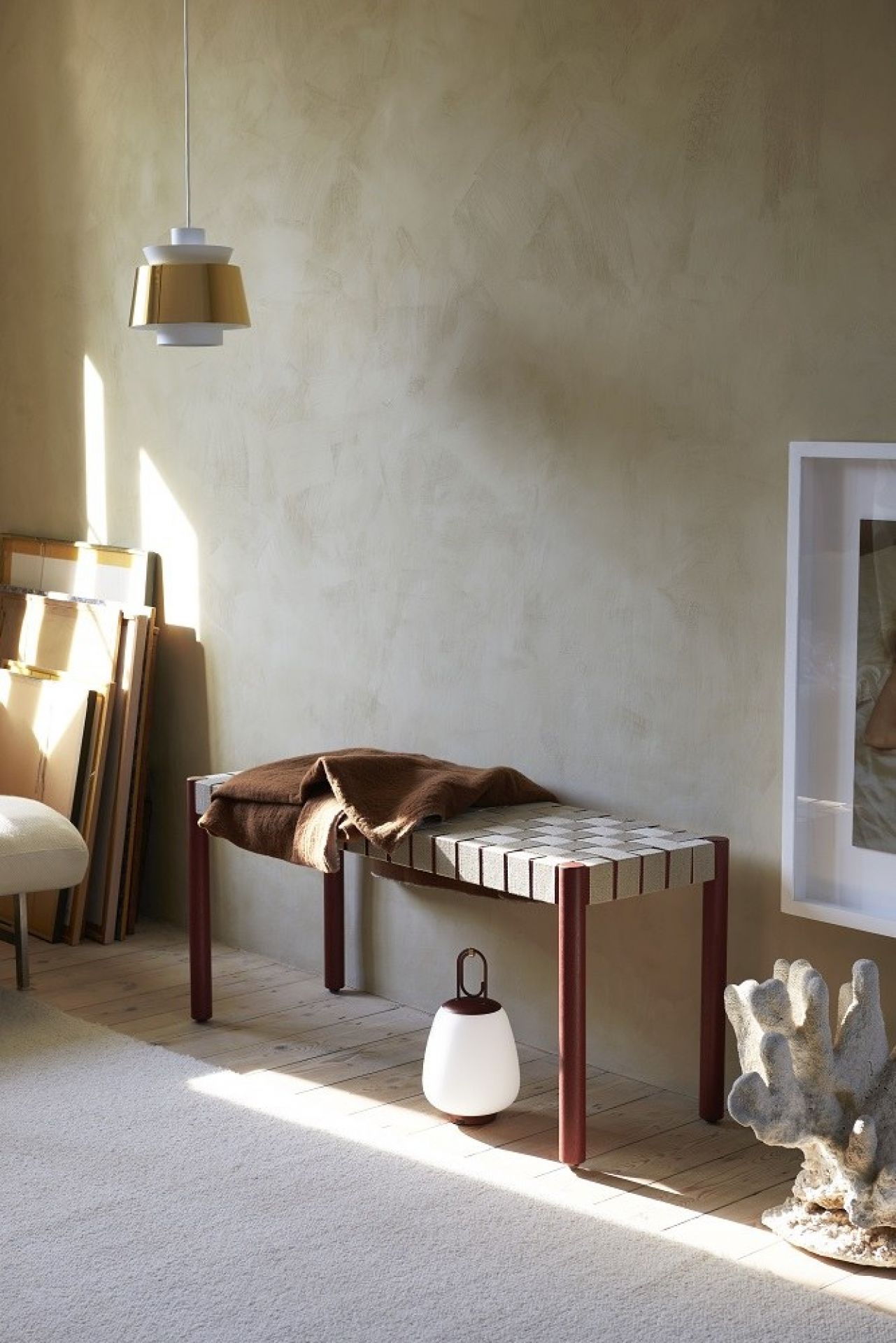 Moderne Bank mit brauner Decke, Lampe und Deko-Objekt im Wohnzimmer. Skandinavisches Design für stilvolles Wohnen.