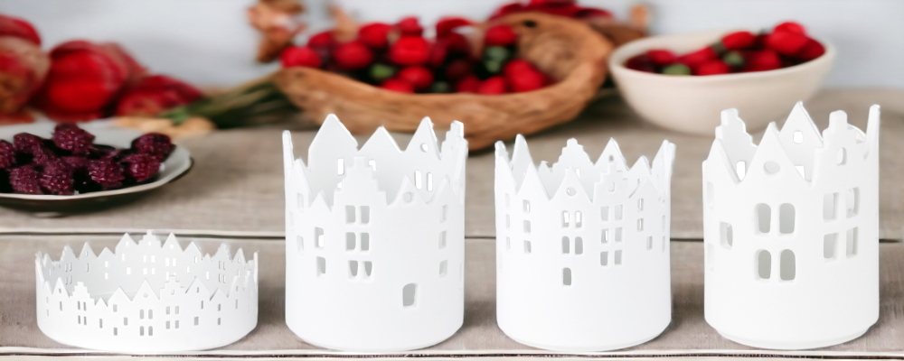 Zuhause Lichthaus Sortiment: Vier weiße Räder Stadtlichter Teelichthalter mit Hausmuster und Fensteröffnungen.