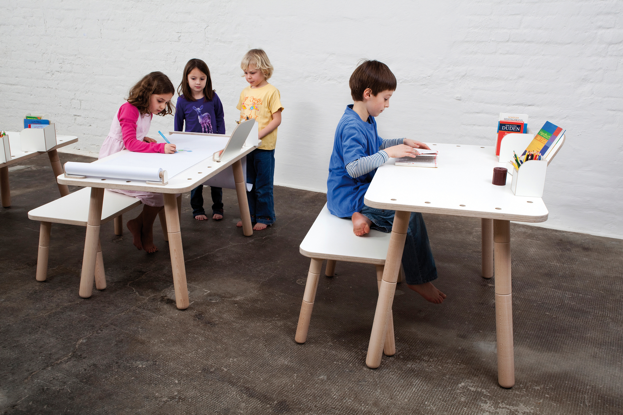 Growing Table Kindermöbel Set: Kinder sitzen an weißen, höhenverstellbaren Kindertischen und malen, lernen und spielen.