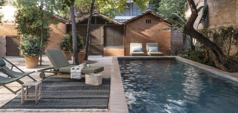 Bild eines grauen Outdoor-Teppichs neben einem Pool mit Liegestühlen und Beistelltisch im Garten.