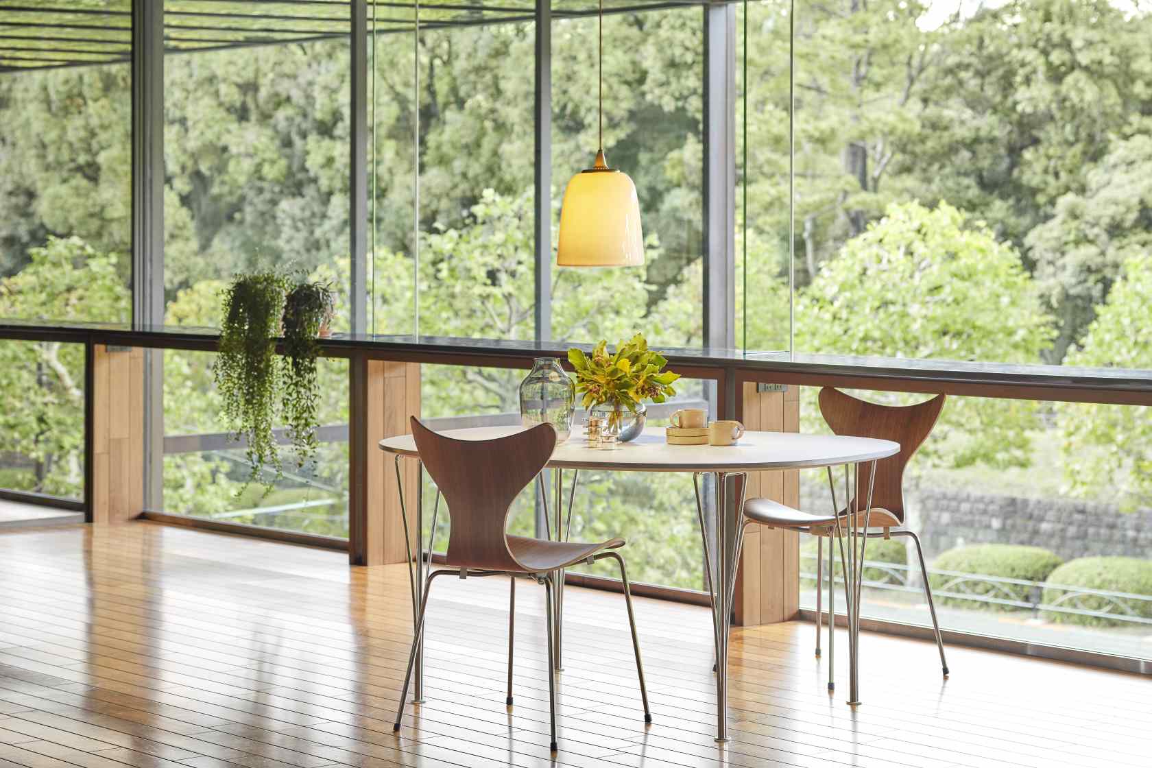 Esszimmer mit rundem Tisch und drei Lily Stühlen 3108 von Fritz Hansen in Holz.
