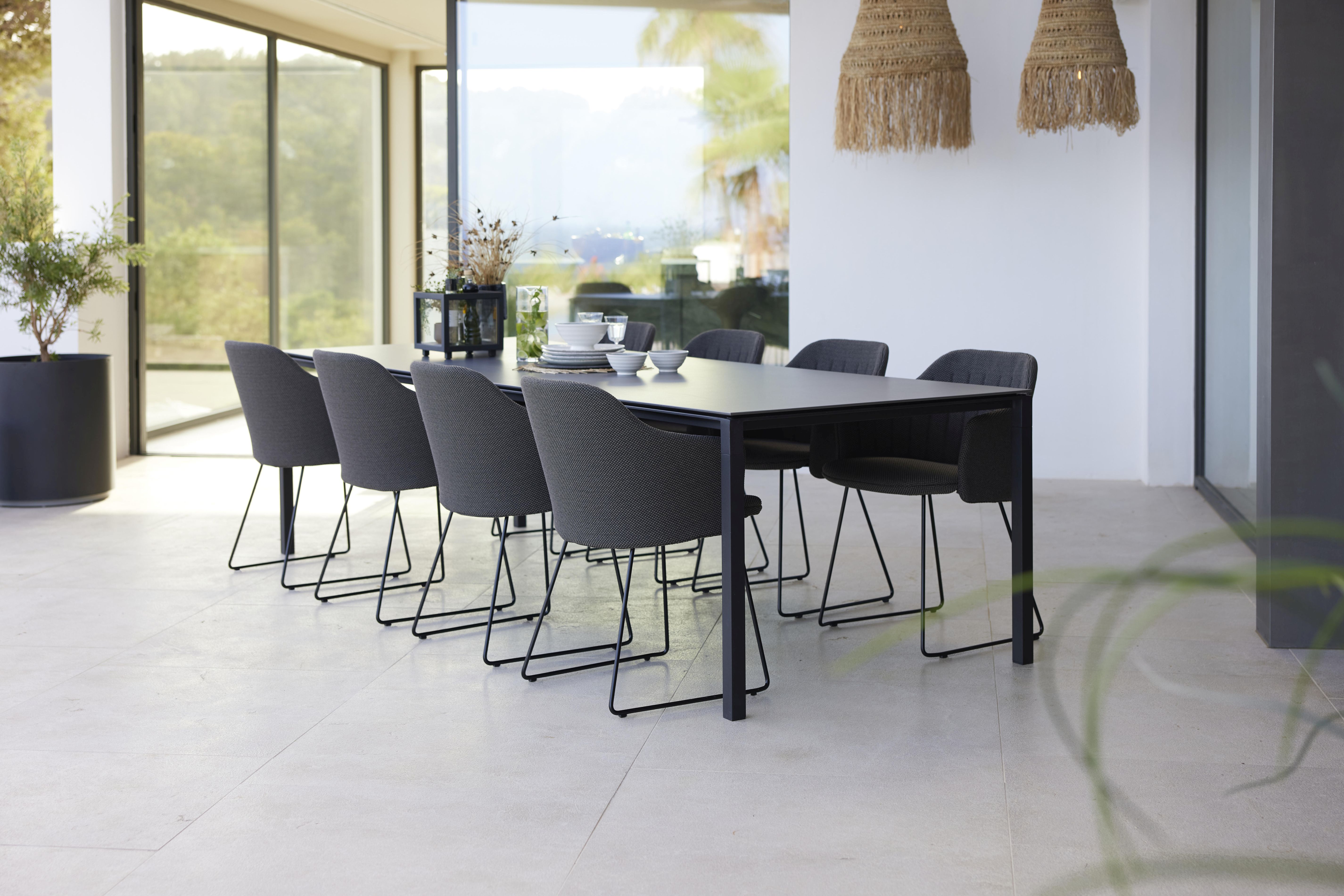 Esstisch mit Cane-Line Choice Outdoor Stühlen, Stahlgestell und grauer Sitzfläche für den Garten.