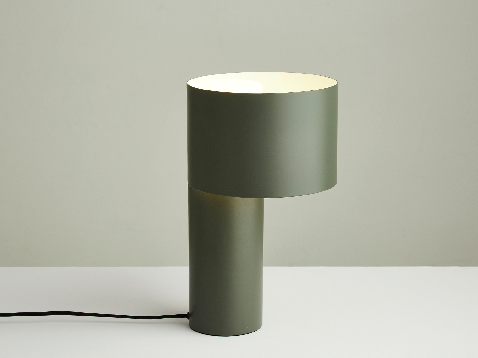 Grüne Tangent Tischleuchte von Woud, moderne Nachttischlampe mit zylindrischem Lampenschirm und warmem Licht.