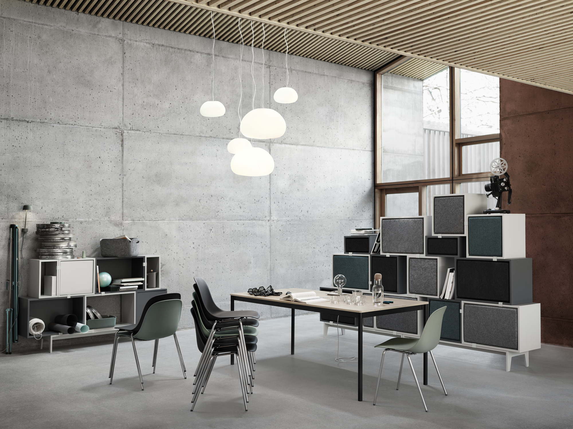 Base Table Round Tisch von Muuto in einem modernen Büro mit Betonwand und Designermöbeln.