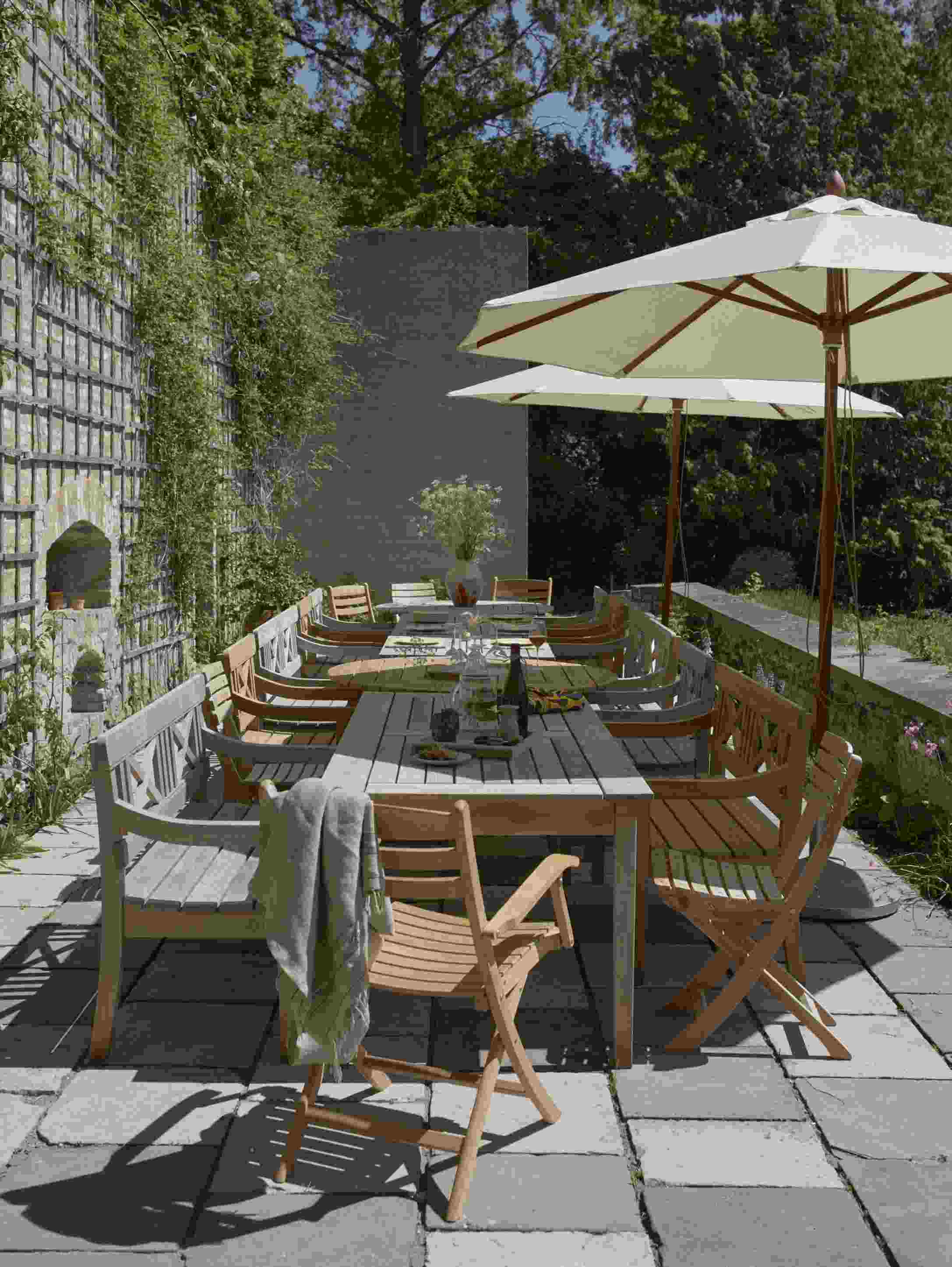 Drachmann Tisch von Skagerak by Fritz Hansen, runder Gartentisch aus Teakholz mit Stühlen und Sonnenschirmen.
