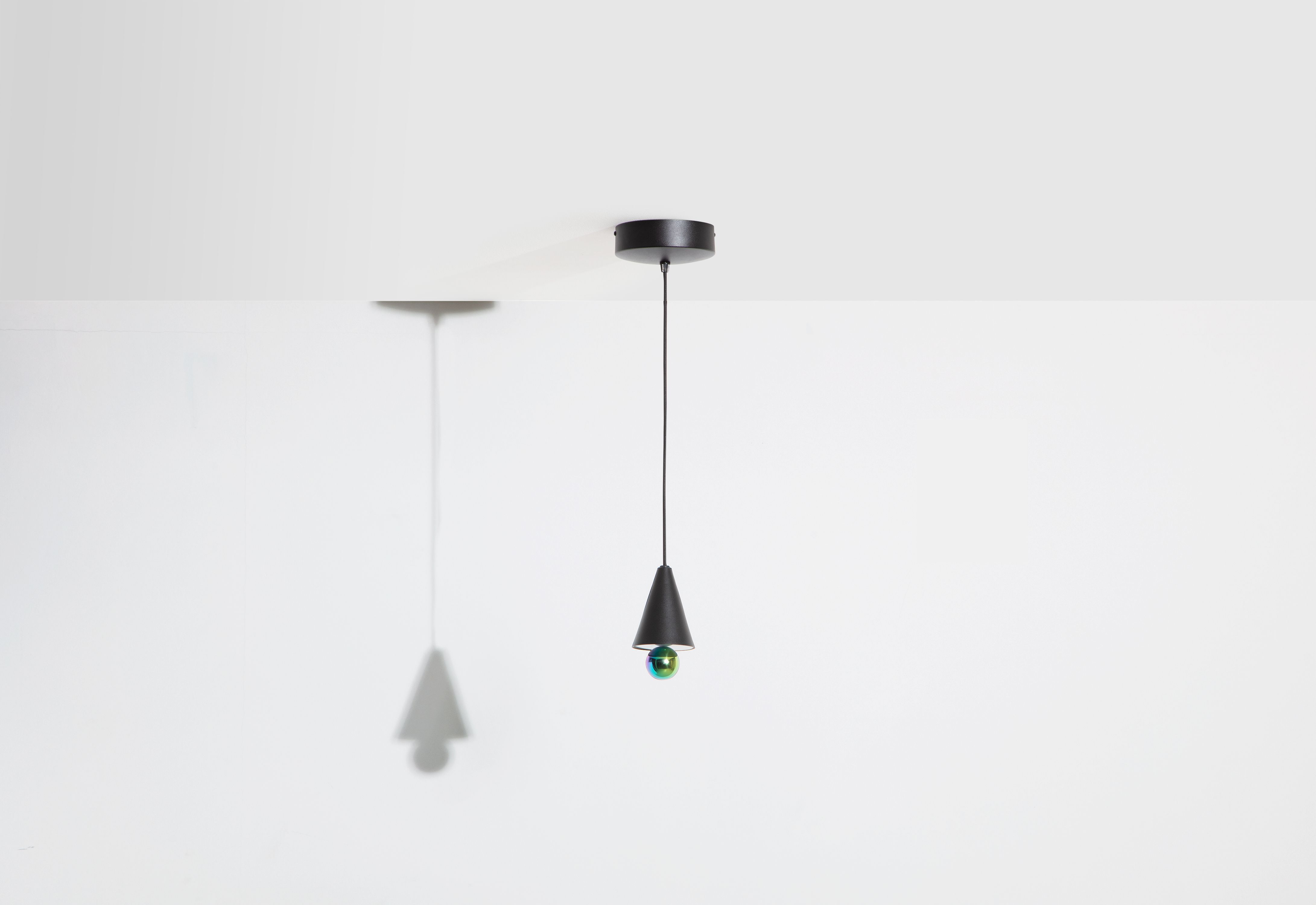 Schwarze Cherry Pendelleuchte von Petite Friture mit schimmernder Kugel und Kegelform vor weißem Hintergrund.