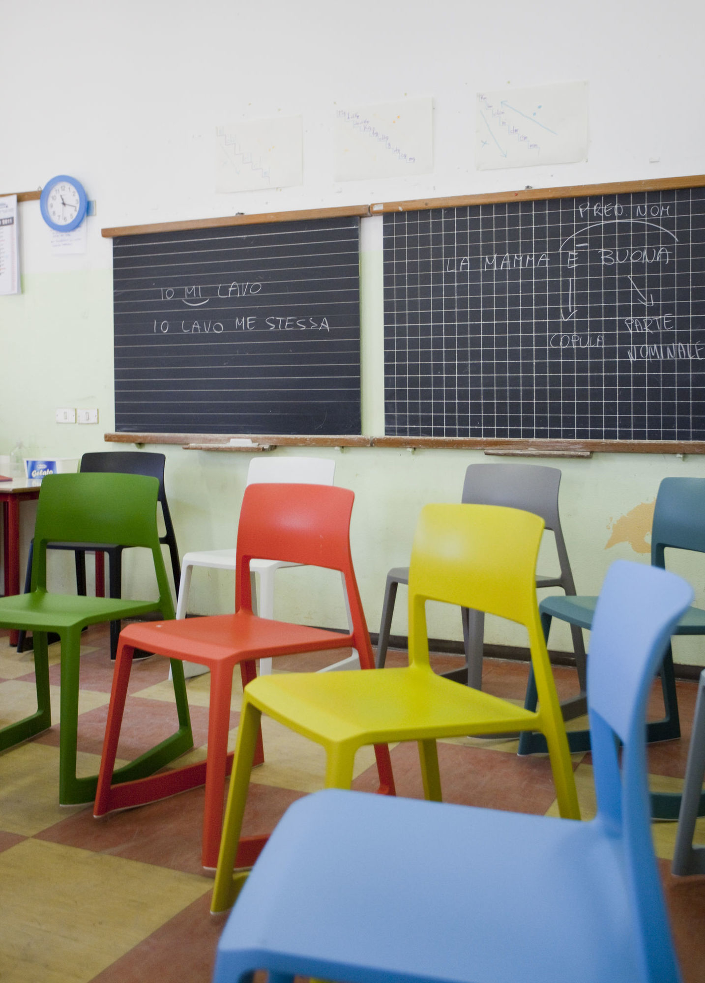 Mehrere Vitra Tip Ton RE Stühle aus Kunststoff in Grün, Rot, Gelb und Blau vor Schultafeln.