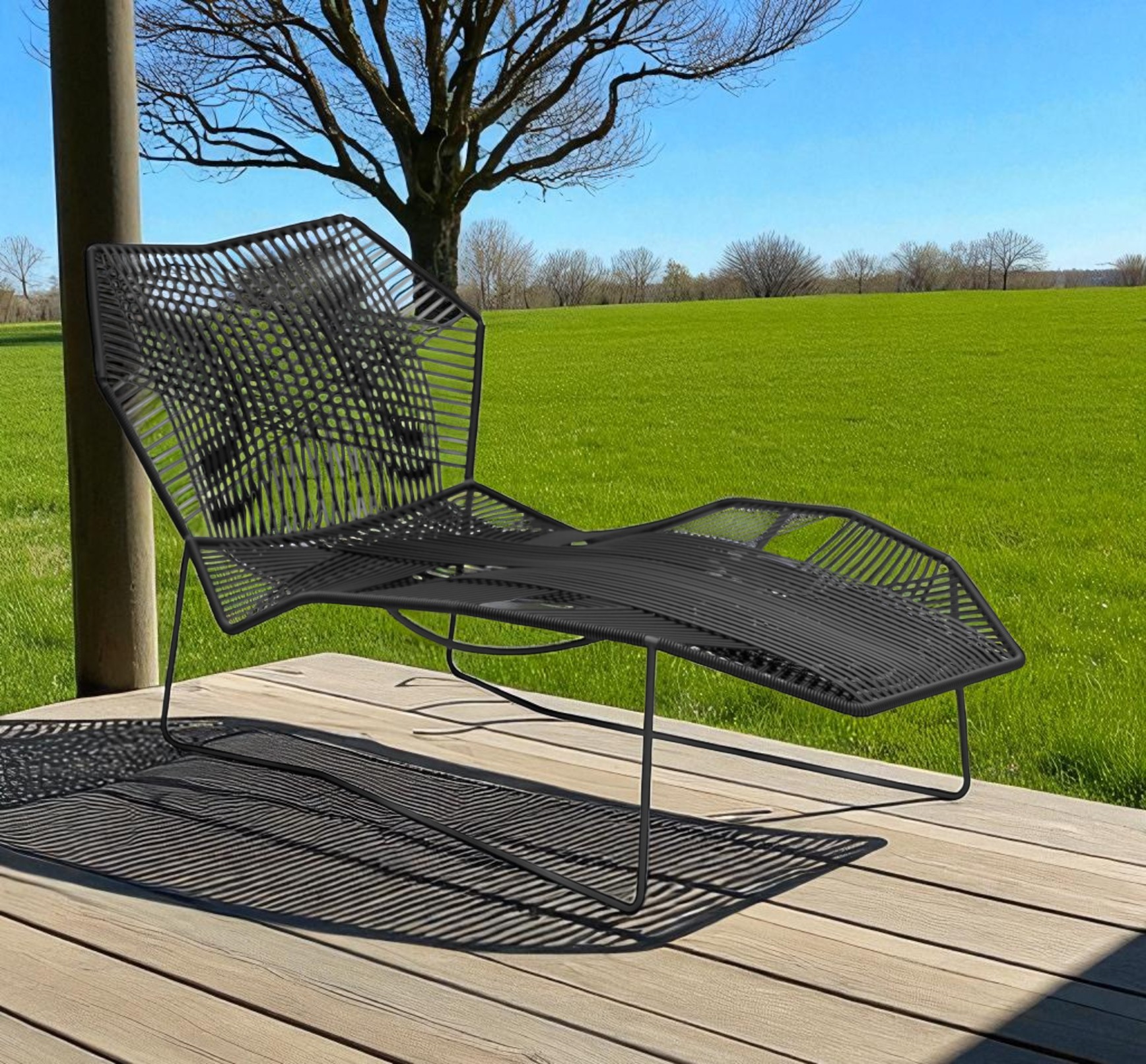 Schwarze Tropicalia TR1 Chaise Longue Outdoor Liege von Moroso auf einer Holzterrasse mit Rasen im Hintergrund.