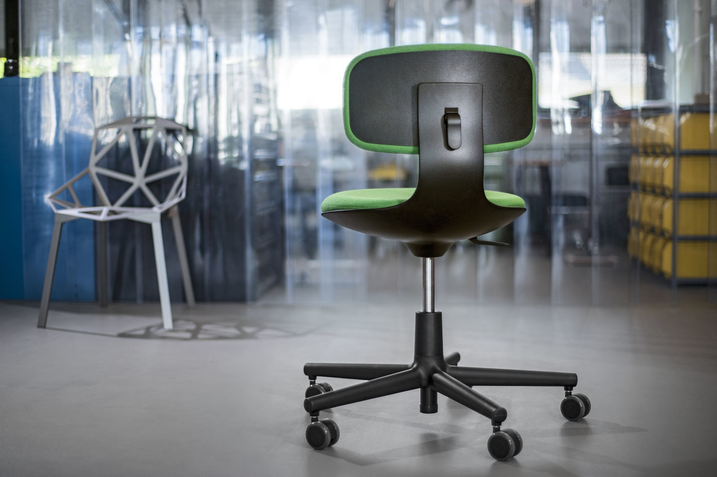 Rückansicht des Vitra Rookie Bürodrehstuhls mit grüner Sitzfläche und Rückenlehne, schwarzem Gestell und Rollen.