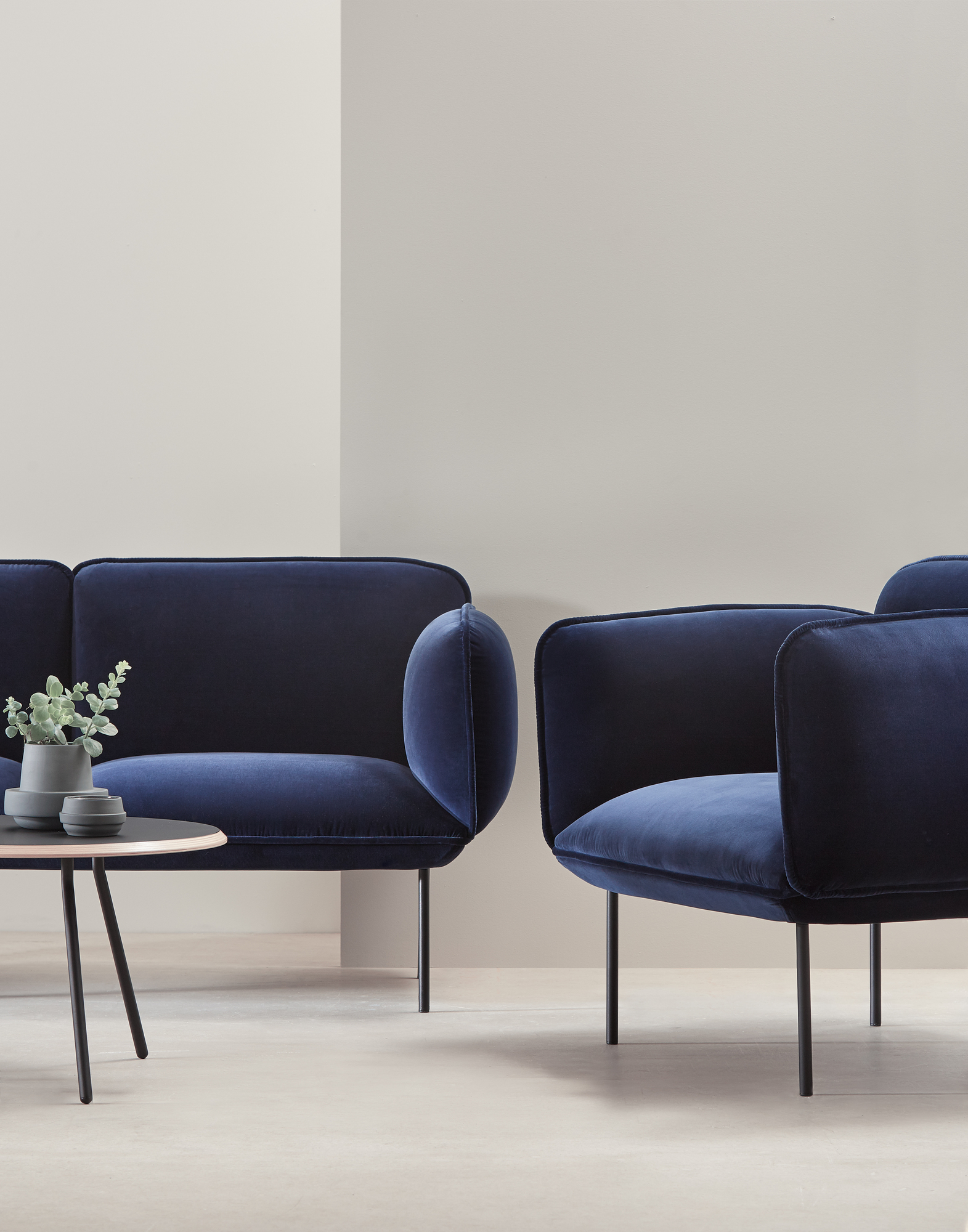Soround Coffee Table von Woud, runder Couchtisch aus schwarzem Metall mit Dekoration und blauen Samt-Sesseln.