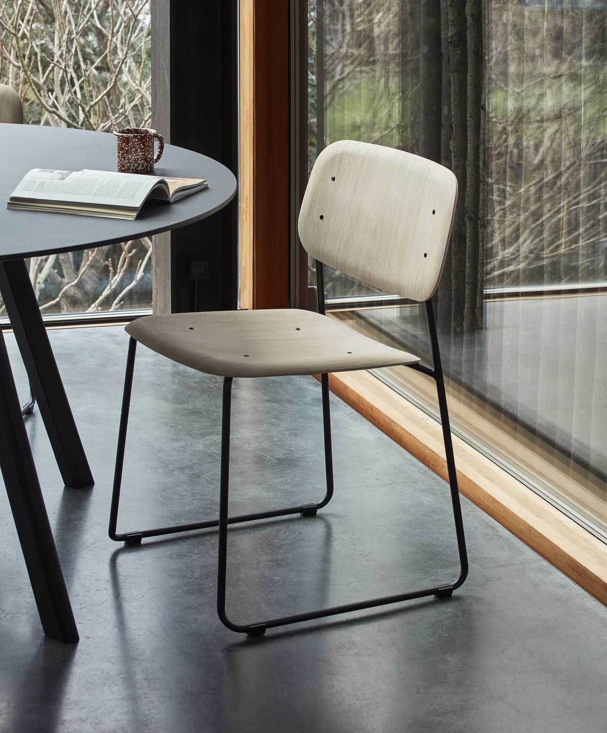 Hay Soft Edge Stuhl 50 mit hellem Holz und schwarzem Metallgestell neben Tisch.