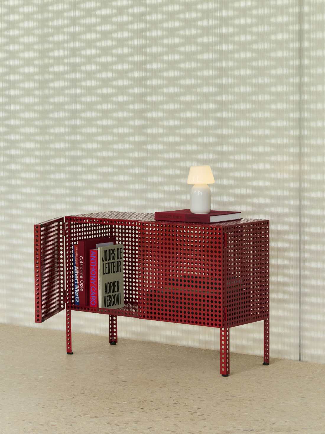 Rotes Hay Perforated Cabinet Sideboard mit Lochmuster, geöffneter Tür, Büchern und Lampe für modernes Wohnen.