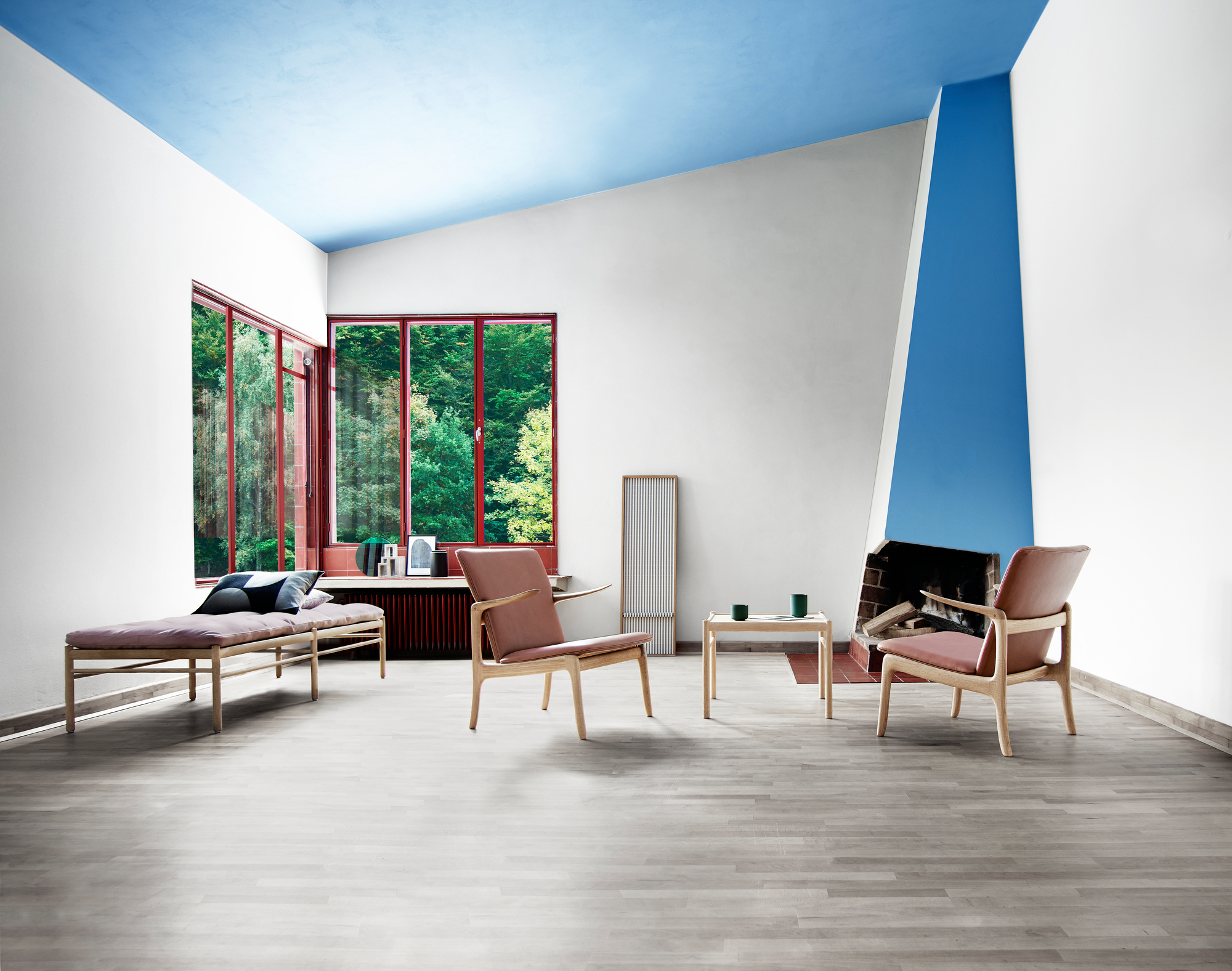 Helles Wohnzimmer mit OW150 Daybed Liege von Carl Hansen, Sessel, Tisch und Kamin für entspannte Stunden.