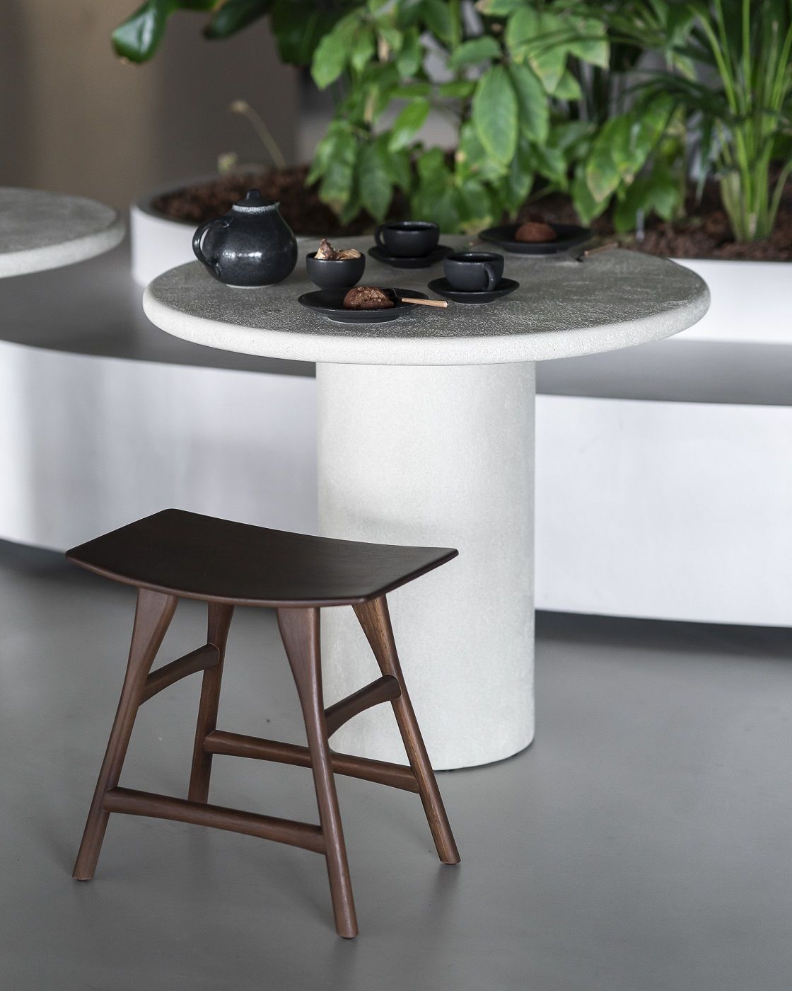 Ethnicraft Elements Esstisch Rund mit Teegeschirr und dunklem Holzstuhl im minimalistischen Interieur.