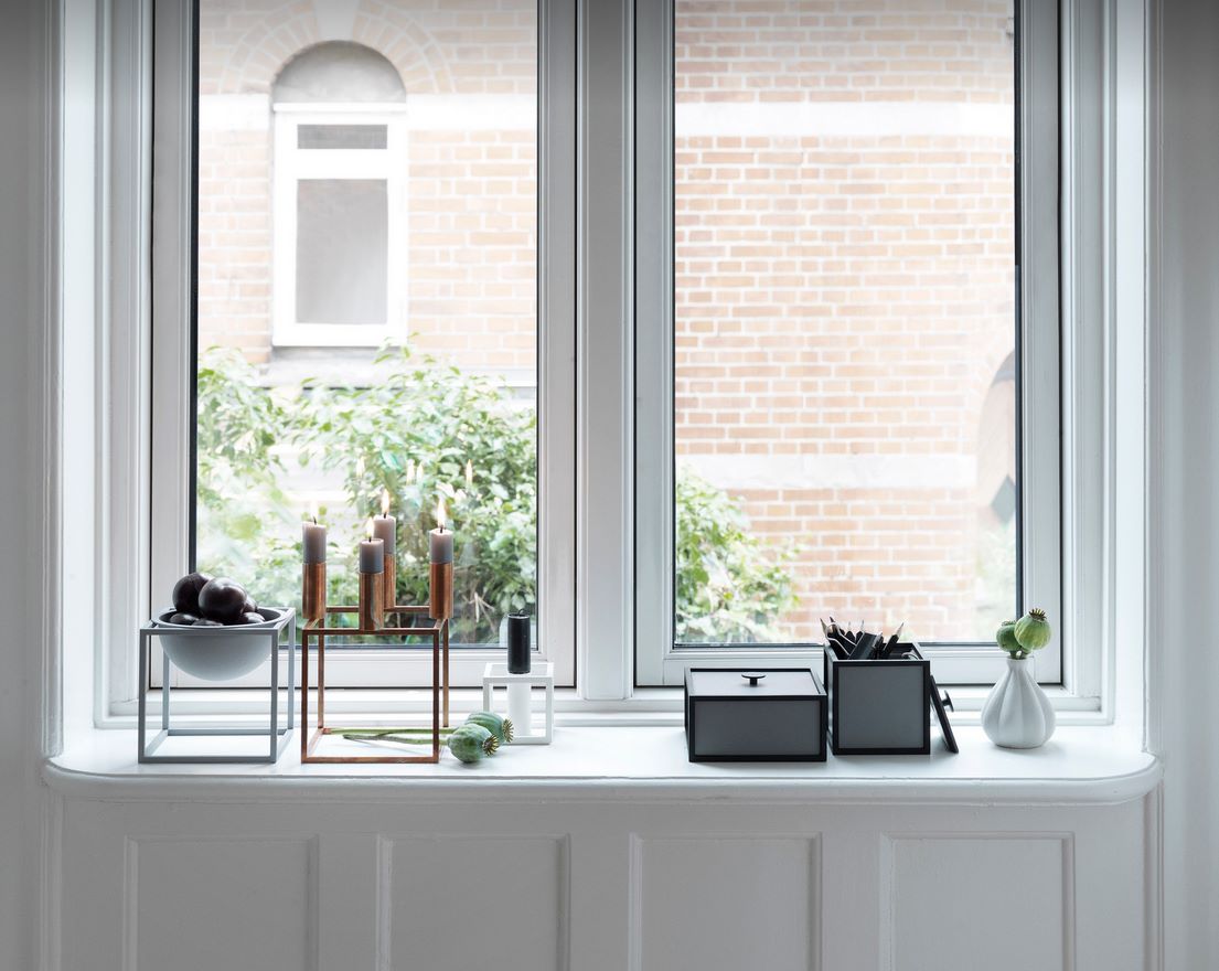 Audo Frame 14 Aufbewahrungsbox in Grau auf einer Fensterbank, neben Deko-Objekten und Kerzen.