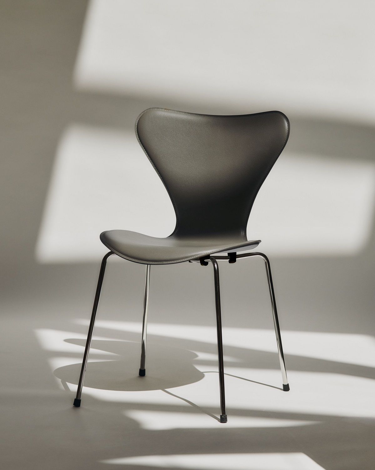 Fritz Hansen Siebener Stuhl mit grauem Lederbezug und Chromgestell im minimalistischen Design.