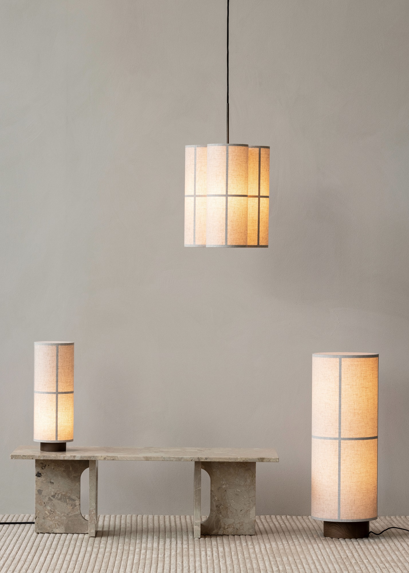 Androgyne Couchtisch von Audo Copenhagen mit zwei Stehlampen und einer Hängelampe in einem minimalistischen Interieur.