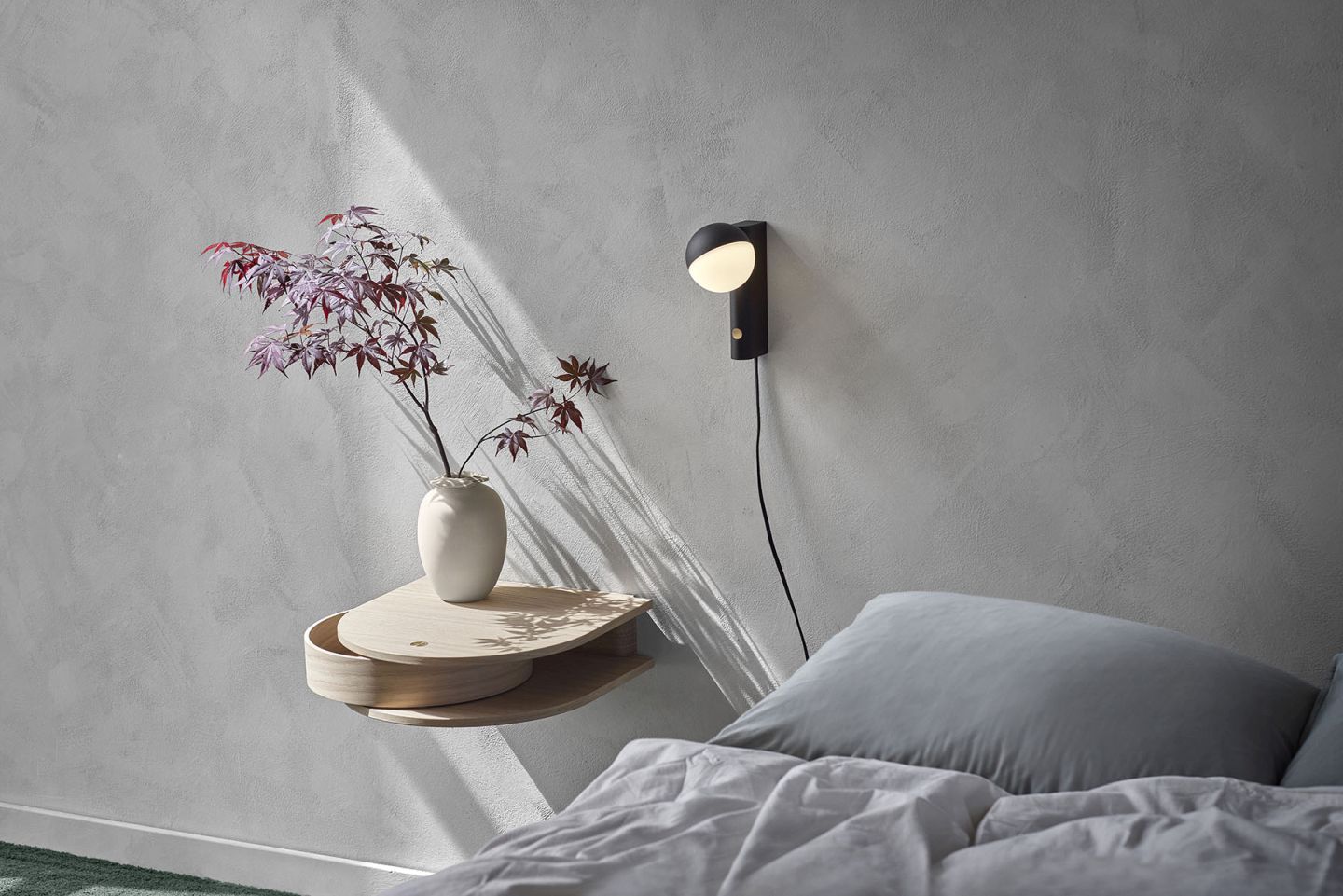 Valet Wandschublade aus geräucherter Eiche neben einer Wandleuchte im Schlafzimmer mit Bett und Dekoration.