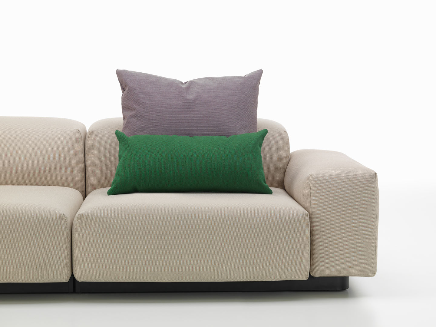 Beige Couch mit einem grünen und einem lila Vitra Kissen, Sofakissen für Wohnzimmer und Lounge.