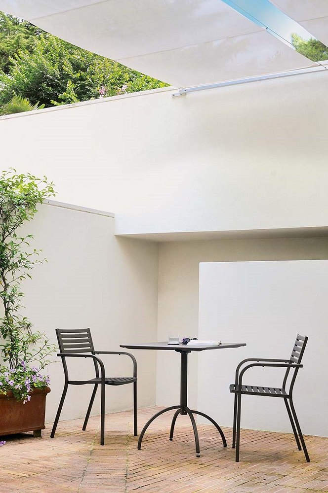 Schwarzer Emu Armlehnstuhl Segno im Außenbereich mit Tisch und Pflanze, Gartenmöbel für Terrasse.