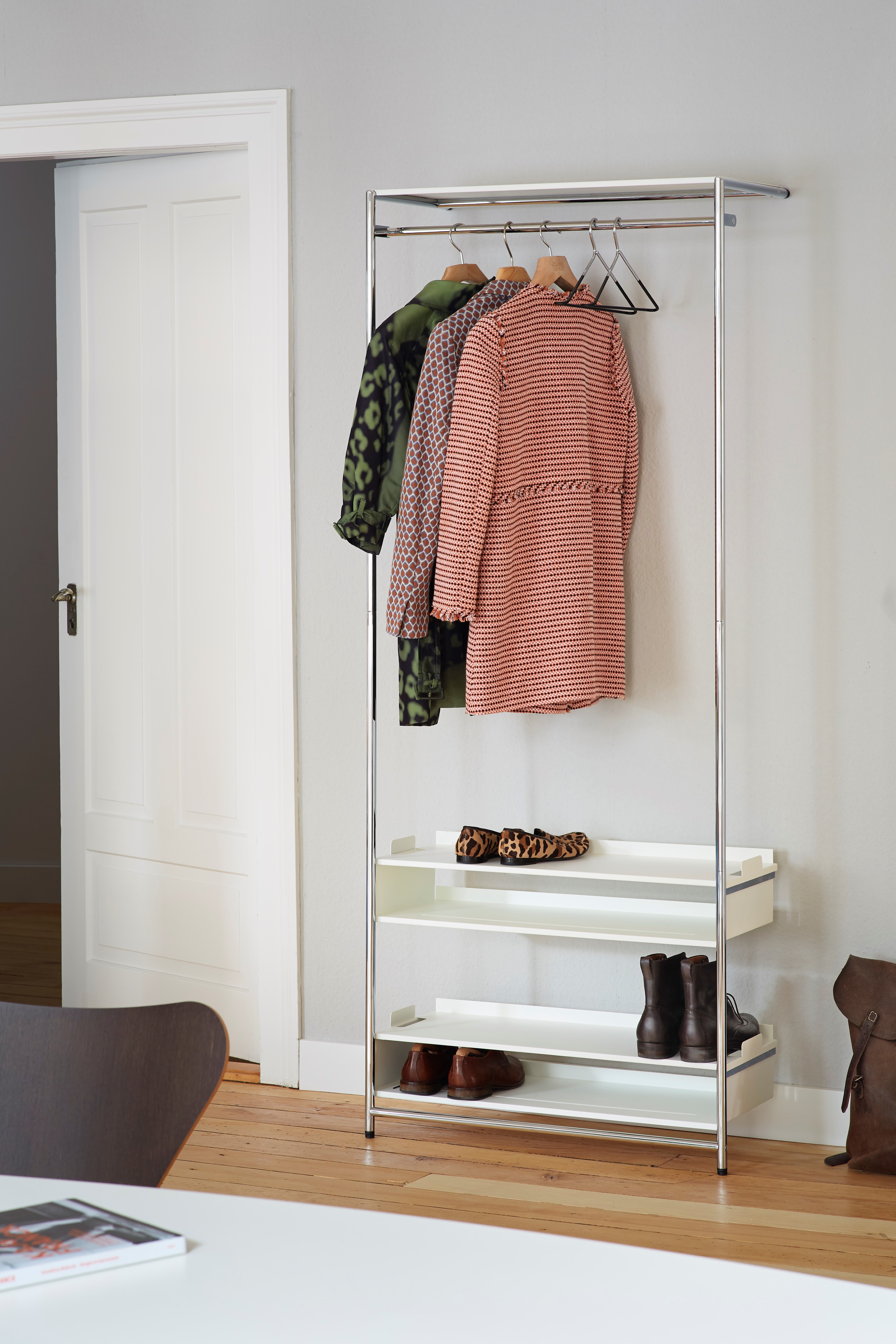 Comba Anlehngarderobe von Mox mit Kleidung und Schuhen auf drei weißen Ablageflächen im modernen Flur.