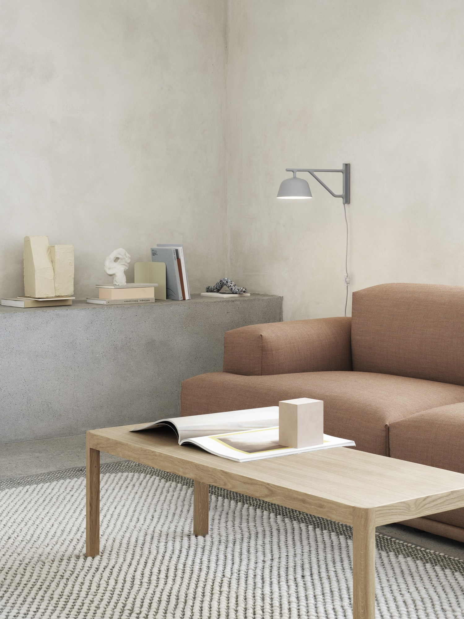 Graue Ambit Wandleuchte von Muuto über Sofa im Wohnzimmer, modernes Design für indirekte Beleuchtung.