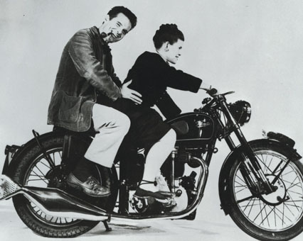 Schwarz-weiß Foto: Mann mit Pfeife und Frau auf einem klassischen Motorrad. Vintage Stil.