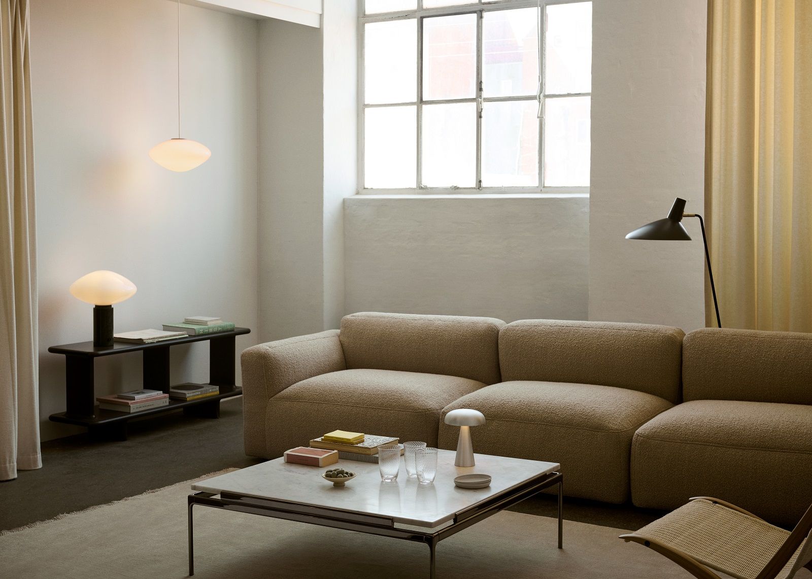 Wohnzimmer mit beigem Sofa, Marmortisch, Lampen und The Moor AP19 Teppich von AndTradition.