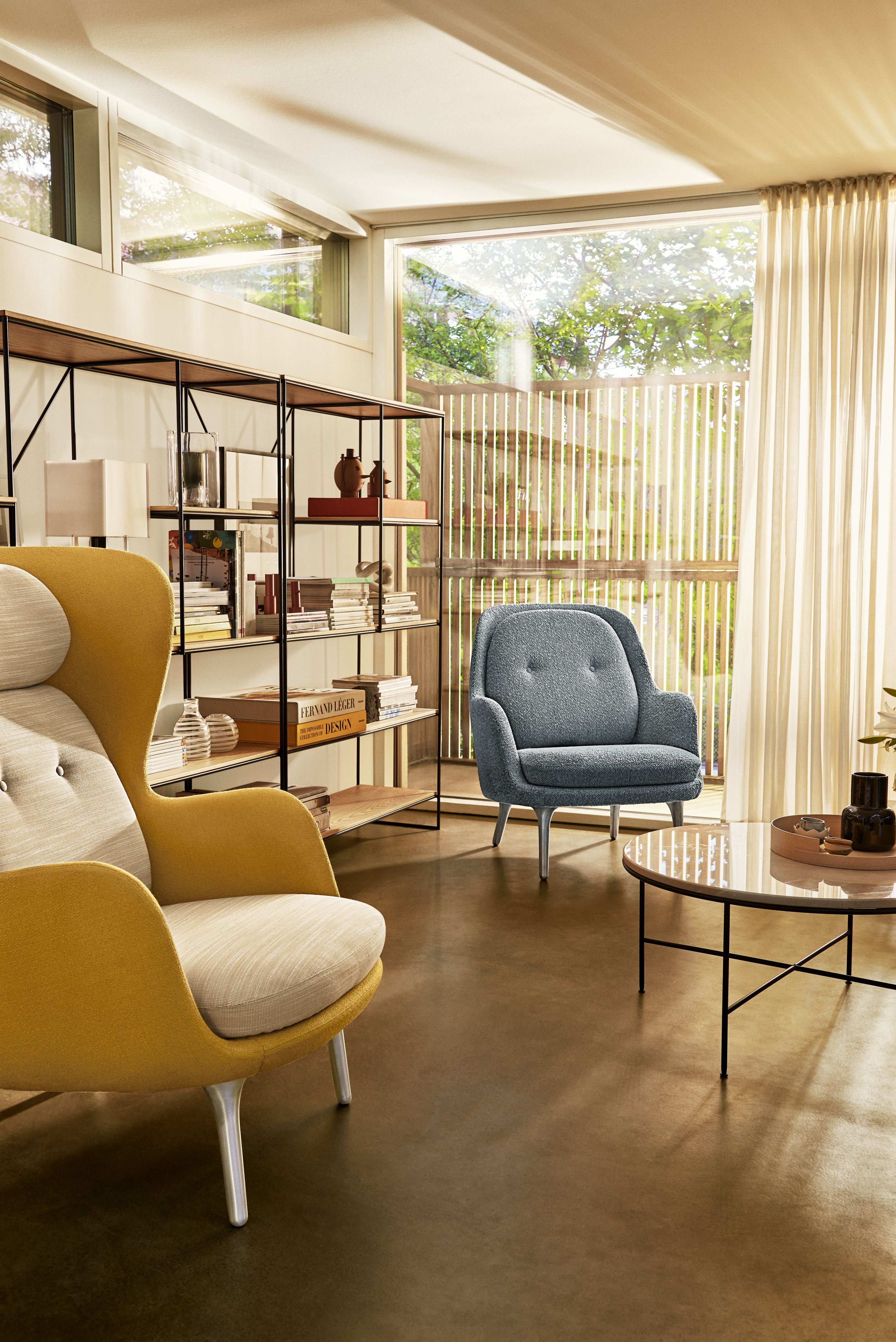 Wohnzimmer mit gelbem Ro Sessel von Fritz Hansen und blauem Sessel neben einem runden Tisch.