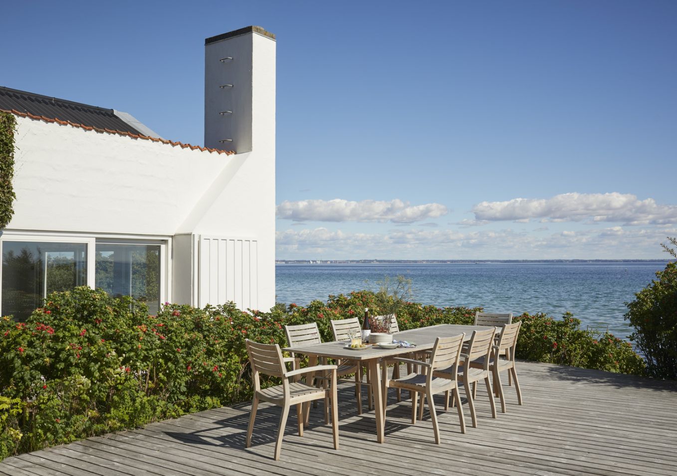 Ballare Chair Stuhl von Skagerak by Fritz Hansen: Gartentisch mit Stühlen auf Holzterrasse am Meer.