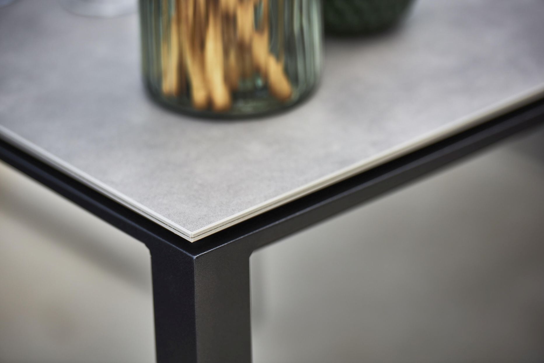 Detailaufnahme der Tischplatte und des Gestells vom Cane-Line Pure Outdoor Esstisch mit grauer Oberfläche.