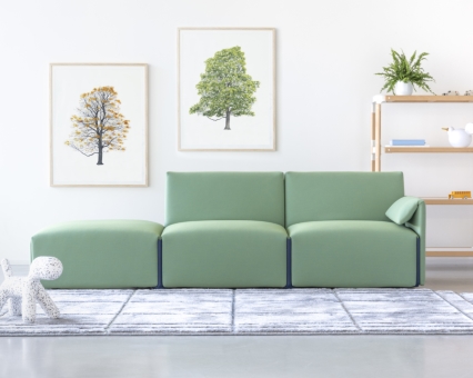 Hellgrünes modulares Sofa mit Ottomane und Kissen im modernen Wohnzimmer mit Teppich und Wandbildern.