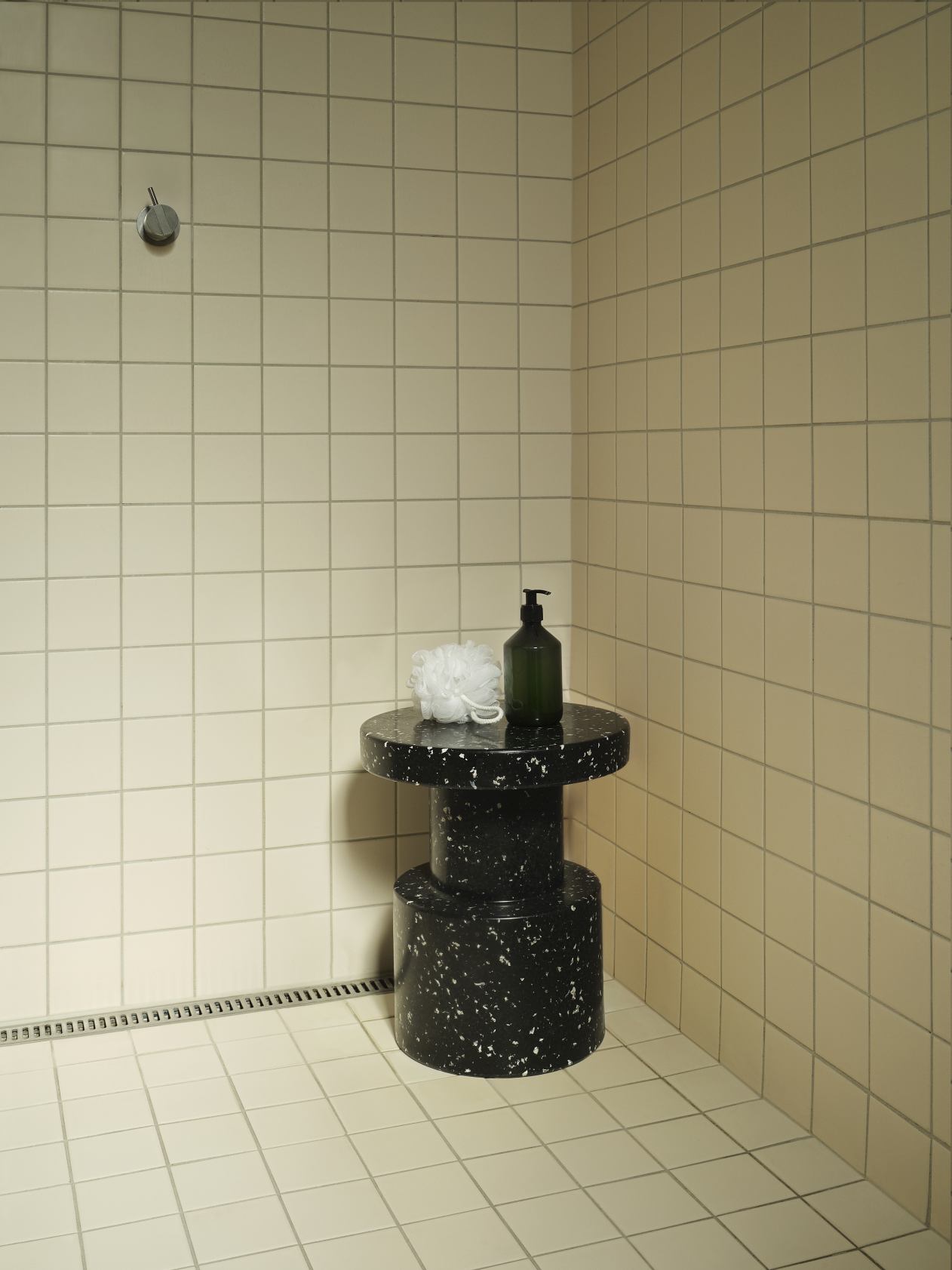 Normann Copenhagen Bit Stool Hocker in Schwarz-Weiß-Optik im Badezimmer mit Seife und Badeschwamm.